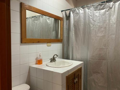 a bathroom with a sink and a shower with a mirror at Hostal Dulces Sueños in Panajachel