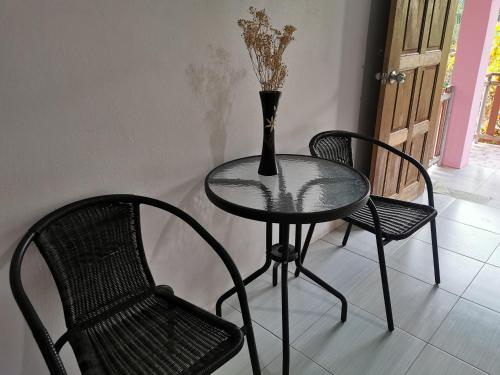 uma mesa de vidro e duas cadeiras e um vaso sobre ela em ชมจันทร์รีสอร์ท ไชยา Chomjan resort 