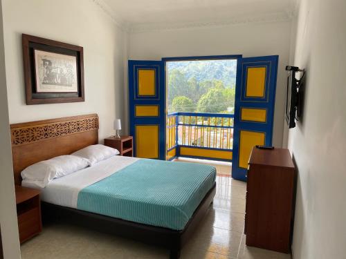 een slaapkamer met een bed en een deur met een balkon bij Hospedaje Camino Real a 150 MTS del centro in Salento