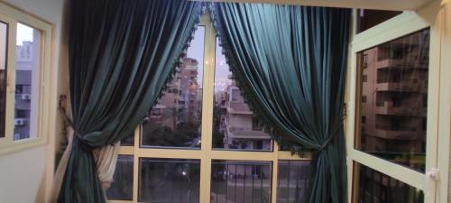 a window with blue curtains and a view of a city at lovely 3 bedroom apartment with 2 balconies and a hot tub in Cairo