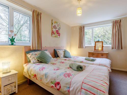 a bedroom with two beds and two windows at Hall Farm Bungalow in Shirley