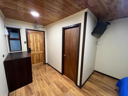 Habitación con puerta, TV y suelo de madera. en Hospedaje Santa Barbara, en Santa Bárbara