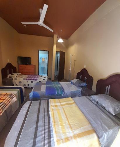 - une chambre avec 3 lits et un ventilateur de plafond dans l'établissement Hospedaje San Miguel, à Luque