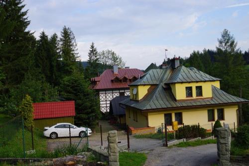 a white car parked in front of a yellow house at Villa Goździk in Wisła