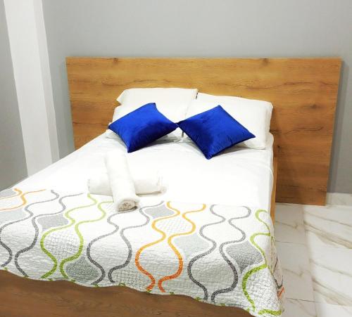 a bed with blue and white pillows and a wooden headboard at Edificio Nuevo Consulado Americano 4Apt Coliving Ecuador in Guayaquil