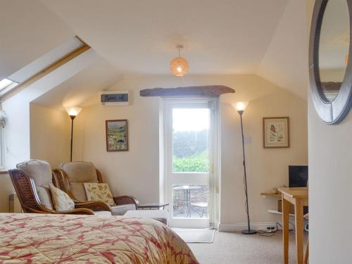 een slaapkamer met een bed, een stoel en een raam bij The Hayloft in Cinderford