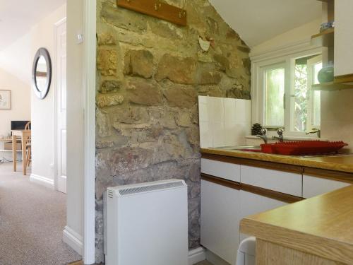 een keuken met een stenen muur en een wastafel bij The Hayloft in Cinderford