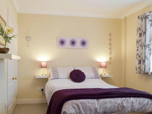 a bedroom with a bed with a purple blanket at Lenas Lodge in Birtsmorton