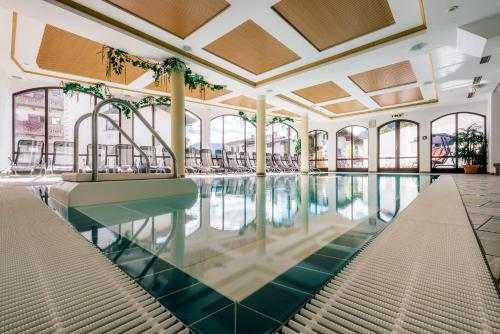 a swimming pool in a building with windows at Hotel Garni Alpenruh-Micheluzzi in Serfaus