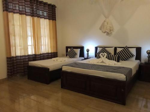 two twin beds in a room with two windows at Isanka Lion Lodge in Sigiriya