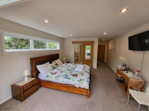 1 dormitorio con 1 cama grande y TV en The perfect getaway for two in a large suite en Whanganui