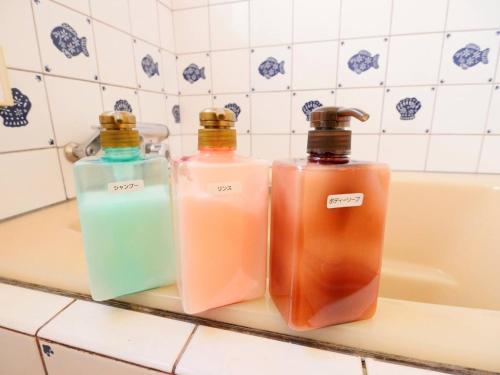 three bottles of soap sitting on a counter next to a bath tub at west crab base - Vacation STAY 13480 in Hiroshima