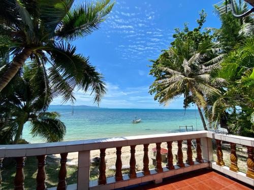 a balcony with a view of the ocean and palm trees at Rainbow Bungalow Haadrin Koh Phangan in Haad Rin