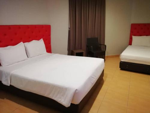 a bedroom with a white bed and a red headboard at SUNTEC HOTEL in Johor Bahru