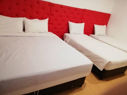 two beds in a room with a red headboard at SUNTEC HOTEL in Johor Bahru