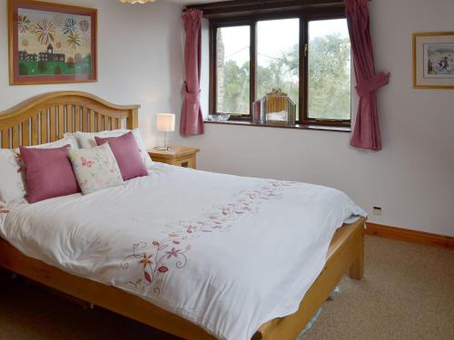 ein Schlafzimmer mit einem großen Bett mit rosa Kissen in der Unterkunft Reubens in Moreleigh