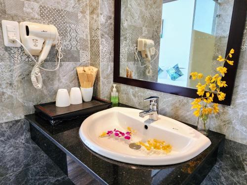 baño con lavabo con flores y teléfono en Vincent's House, en Hoi An