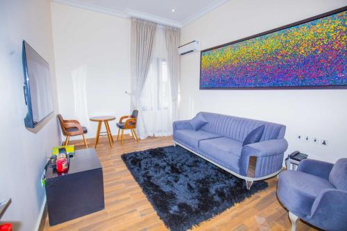 a living room with a blue couch and a painting at Qlets Privé in Abuja