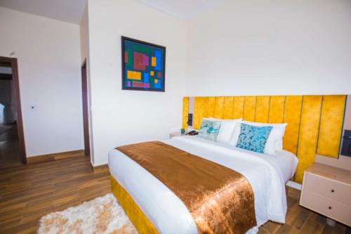 a bedroom with a large bed with a wooden headboard at Qlets Privé in Abuja