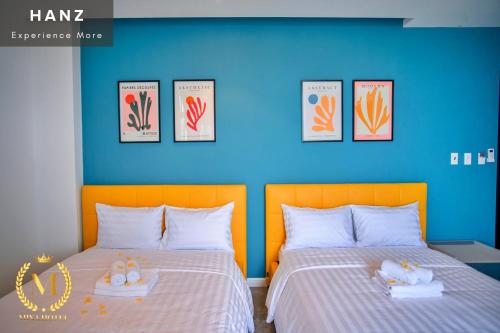 two beds in a room with a blue wall at HANZ Mina Hotel in Ấp Long Khánh