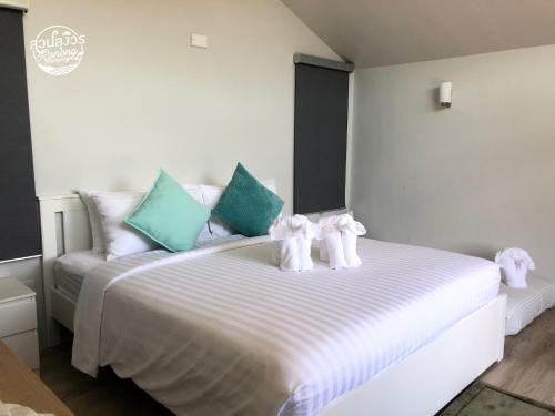 a white bed with two stuffed animals on it at สวนลุงวรRanongGlamping in Ban Bang Hin