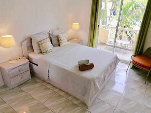 a bedroom with a large white bed and a balcony at Maison à proximité de la plage - LE TAMIER - Flic en Flac in Flic-en-Flac