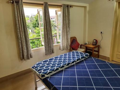 1 dormitorio con cama azul y ventana en Dula HomeStay, en Guwahati