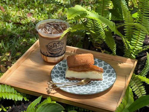 - un plateau en bois avec une assiette de gâteau et une boisson dans l'établissement สวนลุงวรRanongGlamping, à Ban Bang Hin