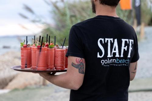 a man holding a tray of red soda cans at Golden Beach Hotel in Chrissi Akti