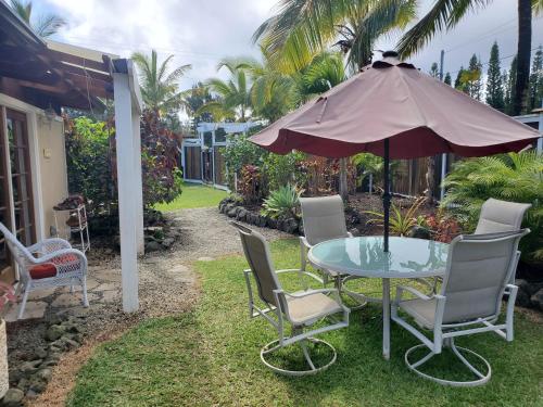 a patio with a table and chairs and an umbrella at Pahoa Paradise Palms in Pahoa