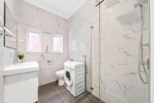 a white bathroom with a toilet and a shower at Burwood Newly Renovated 2 Bedroom Apartment in Sydney