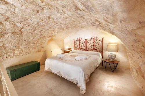 a bedroom with a bed in a stone wall at Dammusi Beneventano in Scicli