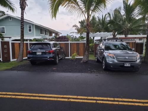two cars parked in a parking lot in front of a house at Pahoa Paradise Palms in Pahoa