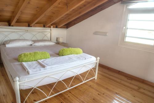 a bedroom with a white bed with green pillows at Iris 3 in Paralia Katerinis