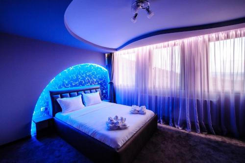 een slaapkamer met een bed in een kamer met blauwe verlichting bij Хотел ПИРГУЛЯ in Miladinowzi