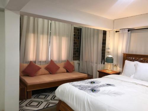 um quarto de hotel com uma cama e um sofá em Chiangmai Lanna em San Kamphaeng