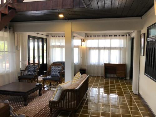 a living room with chairs and a couch and a piano at Chiangmai Lanna in San Kamphaeng