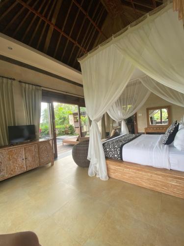 a bedroom with a bed with a canopy at Anggarakasih Ubud Villa in Ubud