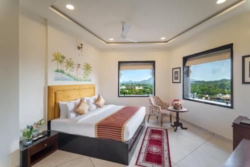 a bedroom with a bed and a desk and window at Traavista Aravali Mahal in Udaipur