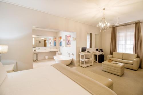 a white bedroom with a bed and a bathroom at Harbour House Hotel - Adventure Pads in Hermanus