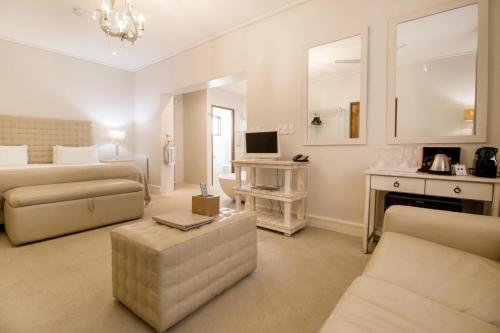 ein weißes Wohnzimmer mit einem Sofa und einem TV in der Unterkunft Harbour House Hotel - Adventure Pads in Hermanus