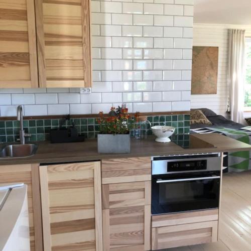 a kitchen with wooden cabinets and a counter top at Svinaberga Skola. Eget boende i gammal skolsal. in Kivik