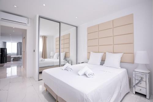 - une chambre blanche avec un grand lit blanc et un miroir dans l'établissement Modern Maubourg - 50m plage - Clim - Terrasse, à Cannes