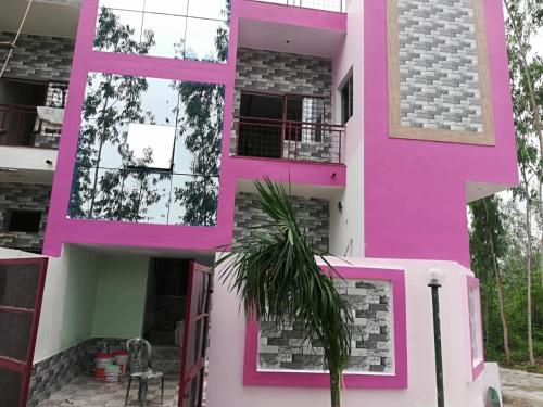 a pink house with a palm tree in front of it at Panna Tiger Home Stay in Khajurāho