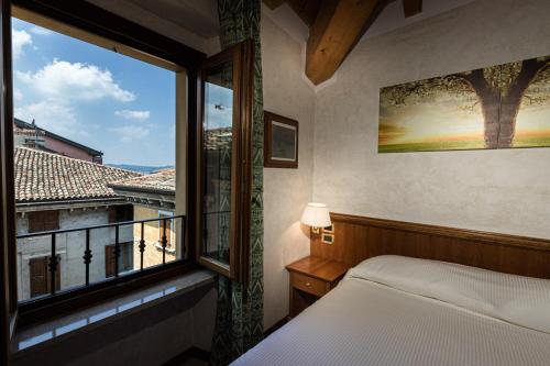 sypialnia z łóżkiem i dużym oknem w obiekcie Hotel Corte Regina w Sirmione