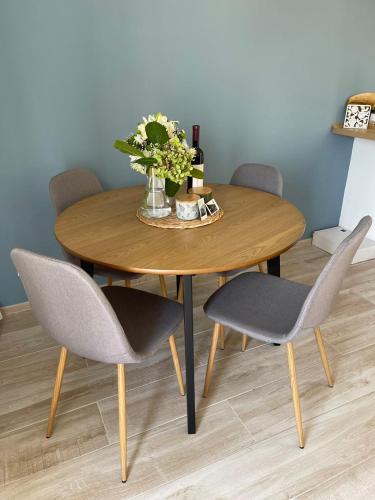 a wooden table with four chairs and a vase of flowers at Chic sea front apartment with breathtaking Kotor Bay view in Donji Stoliv