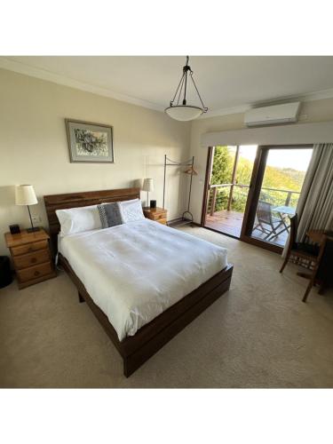 a bedroom with a large bed and a sliding glass door at Valley of the Waters B&B in Wentworth Falls