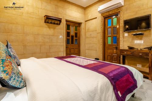 齋沙默爾的住宿－Gaji Hotel Jaisalmer，一间卧室配有一张床,墙上配有电视
