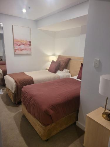 two beds in a hotel room with two beds at CBD Deluxe Private 2 Bedroom Apartment in Adelaide