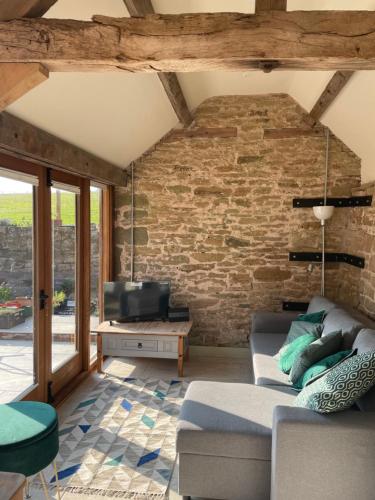 a living room with a couch and a brick wall at Beautiful countryside Byre conversion in Shrewsbury